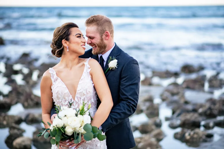 Bride and groom smiling on a rocky beach