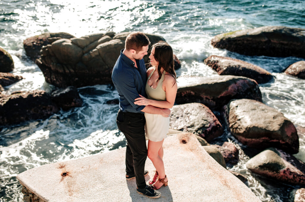 Couple embracing on the rocks by the crashing waves