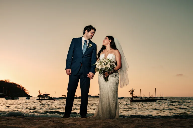 Bride and groom standing on the beach in the evening light