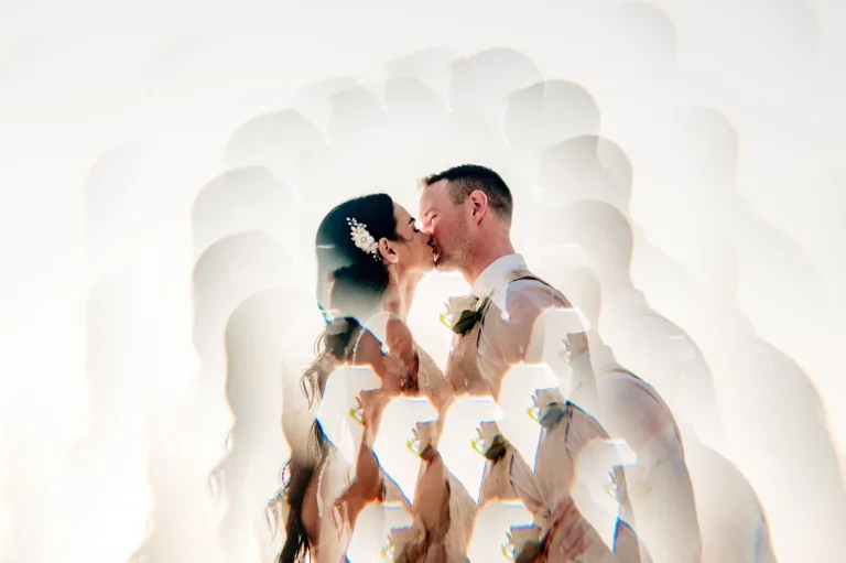 Bride and groom kissing inside a white sculptural archway