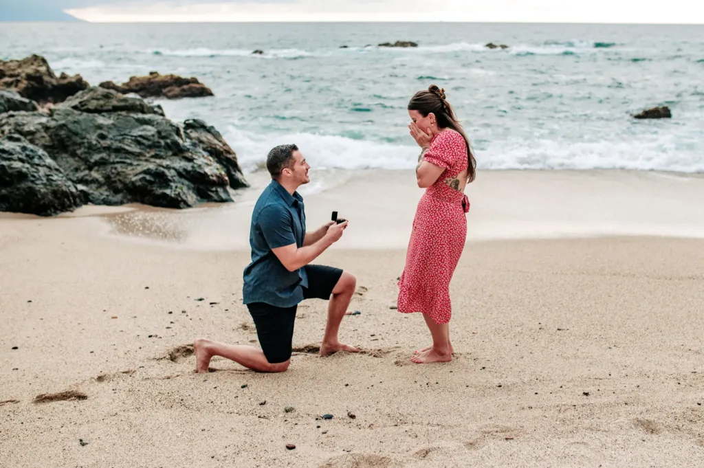 Man proposing on one knee on a sandy beach