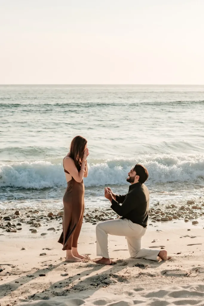 Man proposing on one knee on the beach at sunset